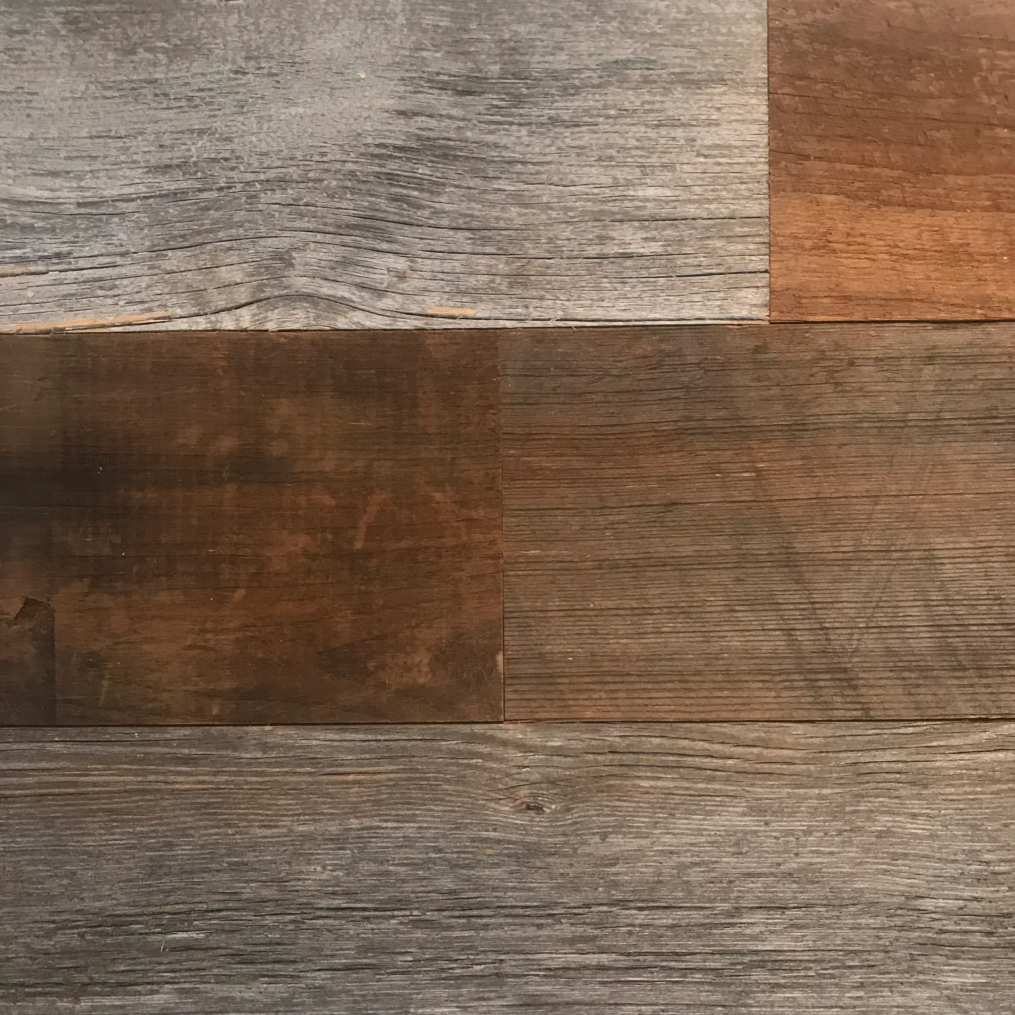 A close-up of Wall & Ceiling Accent Plank features planks in various brown and gray shades, highlighting distinct wood grain patterns and textures. The light to dark colors create a natural, rustic look.