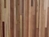 A close-up of a wooden surface with vertical strips of various types and shades, including light, dark, and medium brown tones, showcasing a natural and textured appearance.