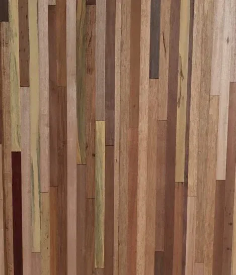 A close-up of a wooden surface with vertical strips of various types and shades, including light, dark, and medium brown tones, showcasing a natural and textured appearance.