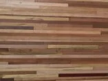 A wooden wall with horizontal strips of various shades and textures, ranging from light tan to dark brown. The different wood grains and colors create a natural, rustic pattern.