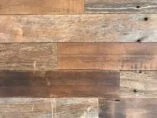 Close-up view of a wooden surface with various shades and textures. The planks are aligned horizontally and show natural grain patterns and knots, creating a rustic appearance.